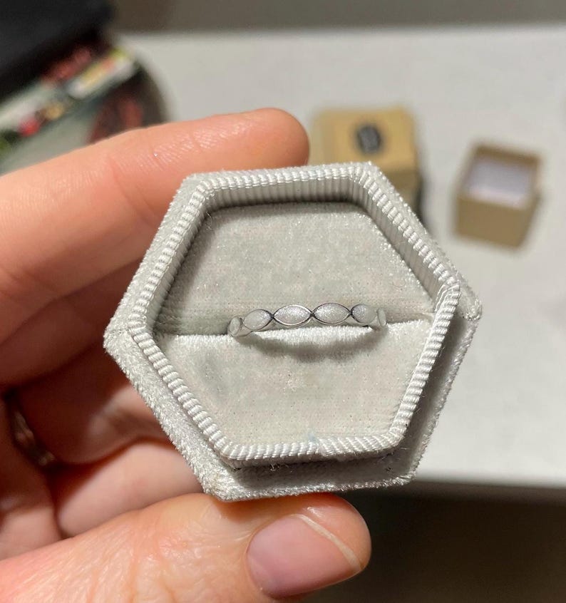 May include: A silver ring with a white enamel design in a gray ring box.