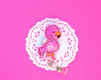 May include: Pink flamingo-shaped retractable badge holder with a white lace doily background.