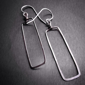 May include: A pair of silver rectangle shaped earrings with a hammered texture.