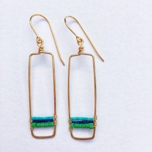 May include: Gold rectangle earrings with green and blue beads. The earrings are long and dangle.