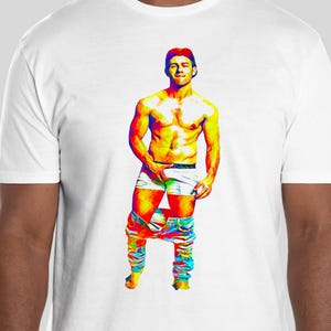 May include: White t-shirt featuring a colorful pop art style illustration of a person with exposed torso and partially lowered pants. The artwork uses a vibrant palette of rainbow colors to depict the figure's form and clothing.
