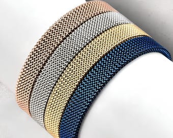 May include: Four woven bracelets in different colors: rose gold, silver, gold, and blue. The bracelets are stacked on top of each other.