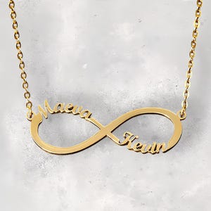 Puede incluir: Collar de infinito de oro con los nombres "Maeva" y "Kevin" grabados.