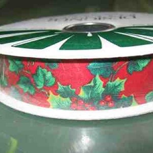 May include: A roll of red and green Christmas ribbon with a holly leaf and berry pattern. The ribbon is on a white spool with a green and white striped design.