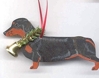 May include: Black and tan dachshund Christmas ornament with a gold bell and a green sprig of holly.