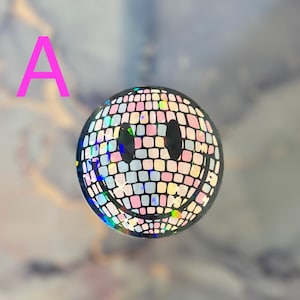 May include: A smiley face sticker with a disco ball design. The sticker is iridescent and has a pink, blue, and white color scheme.