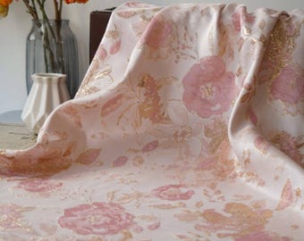 May include: Pink and gold floral fabric with a raised texture. The fabric has a delicate floral pattern with pink flowers and gold accents.