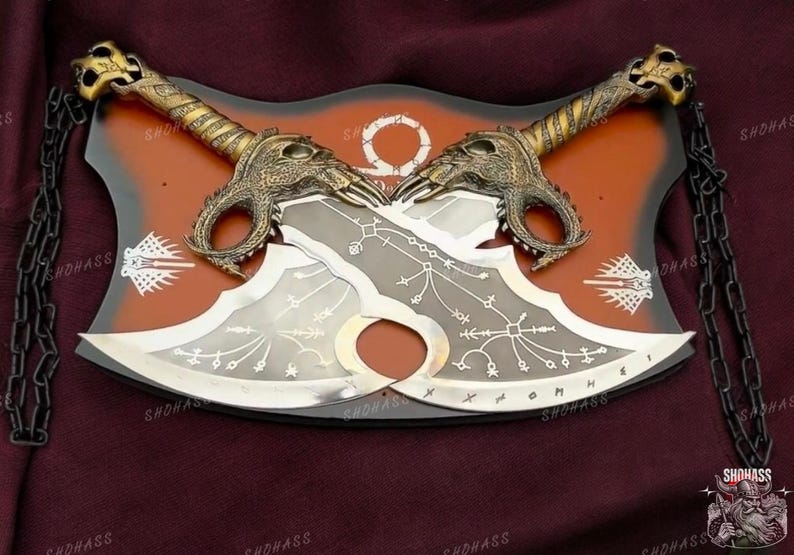 May include: A pair of silver-colored blades with intricate designs, mounted on a red and black wooden plaque. The blades have gold-colored handles with dragon-like heads.