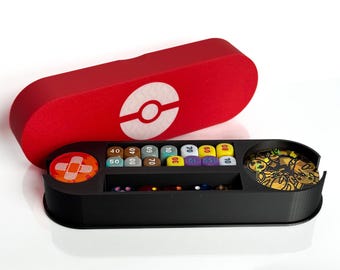 May include: A black and red storage box with a Pokeball design on the lid. The box has compartments for dice, tokens, and other game pieces. The box is open and the compartments are filled with various colored dice and tokens.