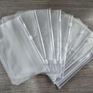 May include: A set of clear plastic zippered pouches with a hole punch design. The pouches are stacked on top of each other and are all the same size.