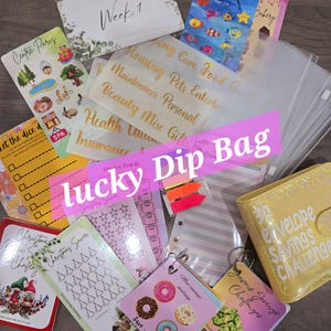 May include: A selection of budgeting and savings tools, including cards with text such as "Week 1", "Fiver Fishing", and "Christmas Saver". Also features clear plastic envelopes, sticky notes, and a yellow glittery envelope savings challenge.