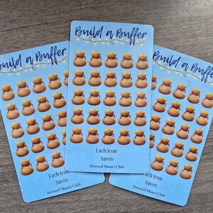 May include: Three blue and white printable stickers with the text "Build a Buffer" and a design of gold coin bags. Each sticker has the text "Each Icon Saves" and "Stressed Mum's Club".