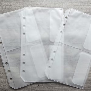 May include: Three clear plastic binder inserts with six punched holes along the left side. Each insert is divided into two horizontal pockets, providing a total of six storage sections for organising documents, cards, or photos in a standard binder.