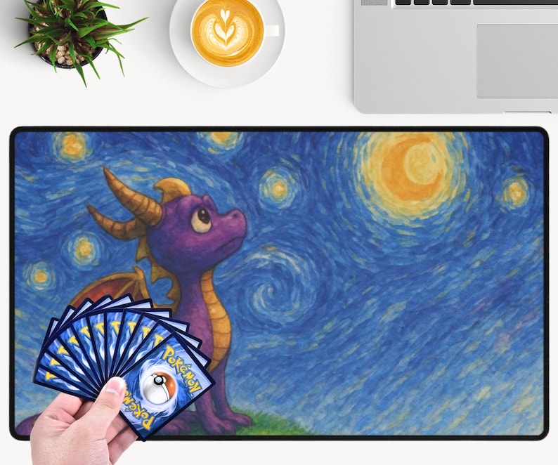May include: A large rectangular mousepad featuring a purple dragon with yellow horns and wings, set against a starry night sky in the style of Van Gogh. A hand holds a fan of Pokemon trading cards. The mousepad is on a white surface.