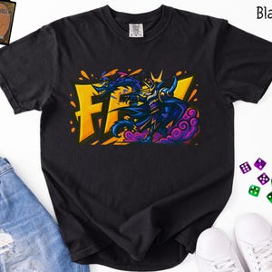 Può includere: T-shirt nero con un design grafico colorato. Il design include le lettere "FF" in giallo, un drago blu e un personaggio in viola e blu. La maglietta è realizzata in un materiale morbido.