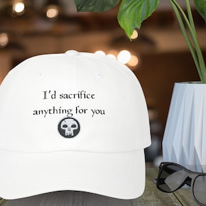 May include: White baseball cap with black embroidered text that reads "I'd sacrifice anything for you" and a black and white skull graphic.