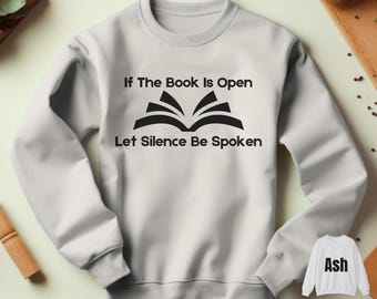 May include: A light gray sweatshirt with black text that reads "If The Book Is Open Let Silence Be Spoken" and a black graphic of an open book.