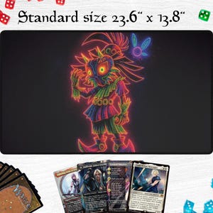 May include: A black gaming mat with a neon-style illustration of a character with a mask and fairy. The mat is 23.6" x 13.8" and features the text "Standard size". Several trading cards and dice are visible.