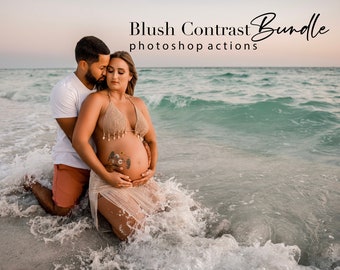 May include: A couple poses on a beach with the ocean in the background. The woman is pregnant and wearing a beige bikini top and a white sheer skirt. The man is wearing a white t-shirt and red shorts. The couple is standing in the water with waves crashing around them.