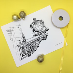 Puede incluir: Un dibujo en blanco y negro de una torre del reloj con detalles ornamentados. La esfera del reloj es visible y la torre está parcialmente oculta por un edificio. El dibujo está sobre un fondo blanco con adornos dorados.