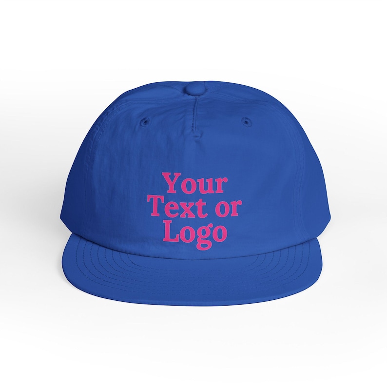 Puede incluir: Gorra de b&eacute;isbol azul real con visera curva. La gorra presenta el texto "Your Text or Logo" en rosa en la parte delantera. La gorra es de color liso, con una corona redondeada y un bot&oacute;n en la parte superior.