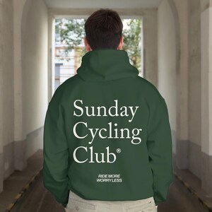Peut inclure: Un sweat à capuche vert foncé avec le texte blanc "Sunday Cycling Club" et la phrase "Ride More Worry Less". Le sweat à capuche a une capuche et est fait d'une matière douce.
