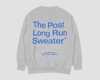 May include: A light gray sweatshirt with the text "The Post Long Run Sweater" in blue on the back. Below the text is the phrase "Run Strong. Rest Well. Repeat."
