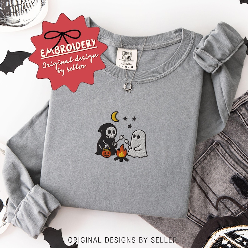 May include: A gray long-sleeve shirt with an embroidered Halloween design. The design features a grim reaper, a ghost roasting marshmallows over a campfire, a crescent moon, and stars. The shirt has the text "EMBROIDERY Original design by seller".