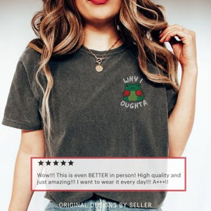 May include: Dark gray t-shirt with a small embroidered frog design. The frog has red boxing gloves and the text "WHY I OUGHTA" is above and below the frog. The shirt has a vintage, worn look.