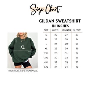 K&ouml;nnte beinhalten: Gr&ouml;&szlig;entabelle f&uuml;r ein Gildan-Sweatshirt, mit Ma&szlig;en in Zoll. Die Tabelle enth&auml;lt die Gr&ouml;&szlig;en S bis 5XL und gibt Breite, L&auml;nge und &Auml;rmelma&szlig;e an. Ein Model, das ein XL-Sweatshirt tr&auml;gt, ist ebenfalls abgebildet.