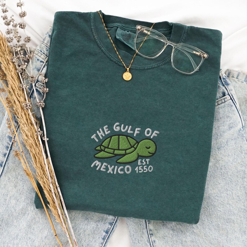 May include: A dark green t-shirt with a white embroidered sea turtle and the text "The Gulf of Mexico Est 1550".