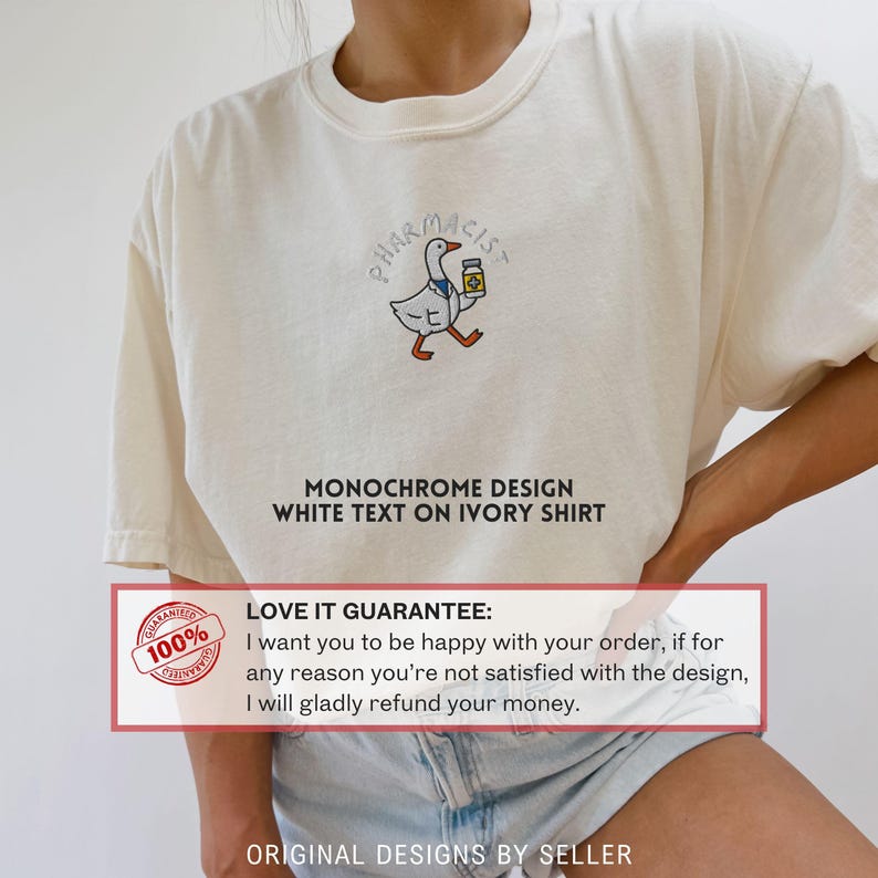 May include: Ivory-colored t-shirt featuring a cartoon goose wearing a pharmacist's coat and holding a medicine bottle. The word "PHARMACIST" is arched above the goose. Below the goose is the text "MONOCHROME DESIGN WHITE TEXT ON IVORY SHIRT".