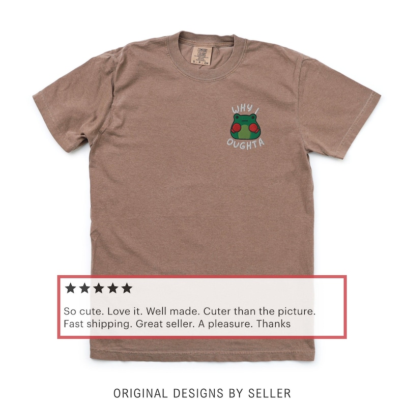 May include: Brown t-shirt with a small embroidered frog graphic. The frog has green skin, red cheeks, and the text "WHY I OUGHTA" above it. The shirt has a crew neck and short sleeves.
