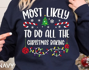May include: Navy blue Christmas sweatshirt with the text "Most Likely To Do All The Christmas Baking" with a Christmas tree, candy canes, snowflakes, and Christmas lights.