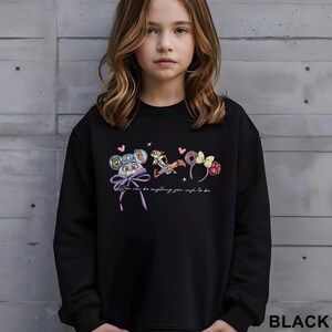 Puede incluir: Sudadera negra con dise&ntilde;os de personajes de dibujos animados coloridos y el texto "You can be anything you wish to be". El dise&ntilde;o incluye un rat&oacute;n con un lazo, un zorro y unas orejas con una rosquilla y frambuesas.