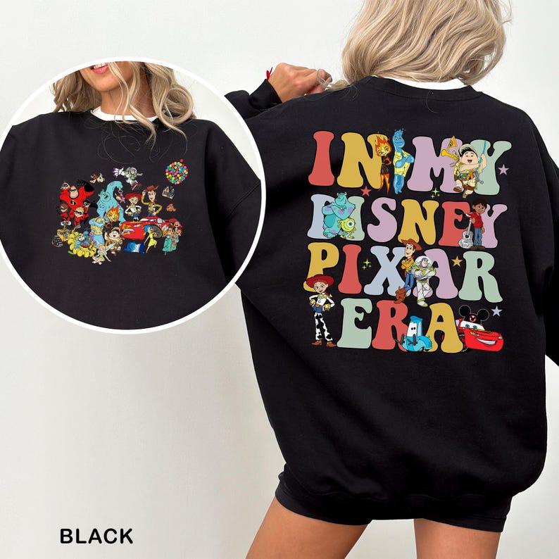 May include: Black sweatshirt featuring a colorful graphic of Disney Pixar characters and the text "IN MY DISNEY PIXAR ERA" in a retro font. The sweatshirt has a crew neck and long sleeves. The design includes characters from various Pixar films.