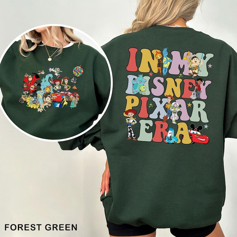 May include: Forest green sweatshirt featuring a colorful graphic of Disney Pixar characters on the front and the phrase "IN MY DISNEY PIXAR ERA" on the back. The sweatshirt has a crew neck and long sleeves, perfect for casual wear.