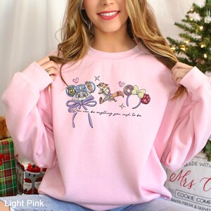 Puede incluir: Sudadera rosa claro con dise&ntilde;os de personajes de dibujos animados y el texto "You can be anything you wish to be." El dise&ntilde;o incluye un conejito, un zorro y diademas en forma de rosquilla. La sudadera es rosa claro.