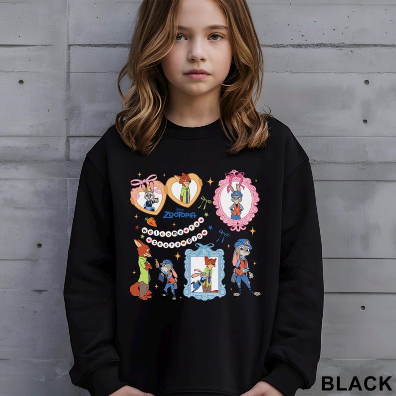May include: Black sweatshirt featuring colorful cartoon images of characters from the movie Zootopia. The design includes framed portraits of the characters and the word "Zootopia". The sweatshirt is made of a soft material.