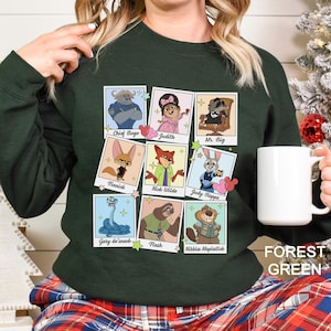 Puede incluir: Sudadera verde bosque con un collage de retratos de personajes de dibujos animados. Los personajes incluyen a Chief Bogo, Judith, Mr. Big, Finnick, Nick Wilde, Judy Hopps, Gary de'snack, Flash y Nibbles Maplestick. El texto "FOREST GREEN" est&aacute; impreso en la parte inferior derecha.