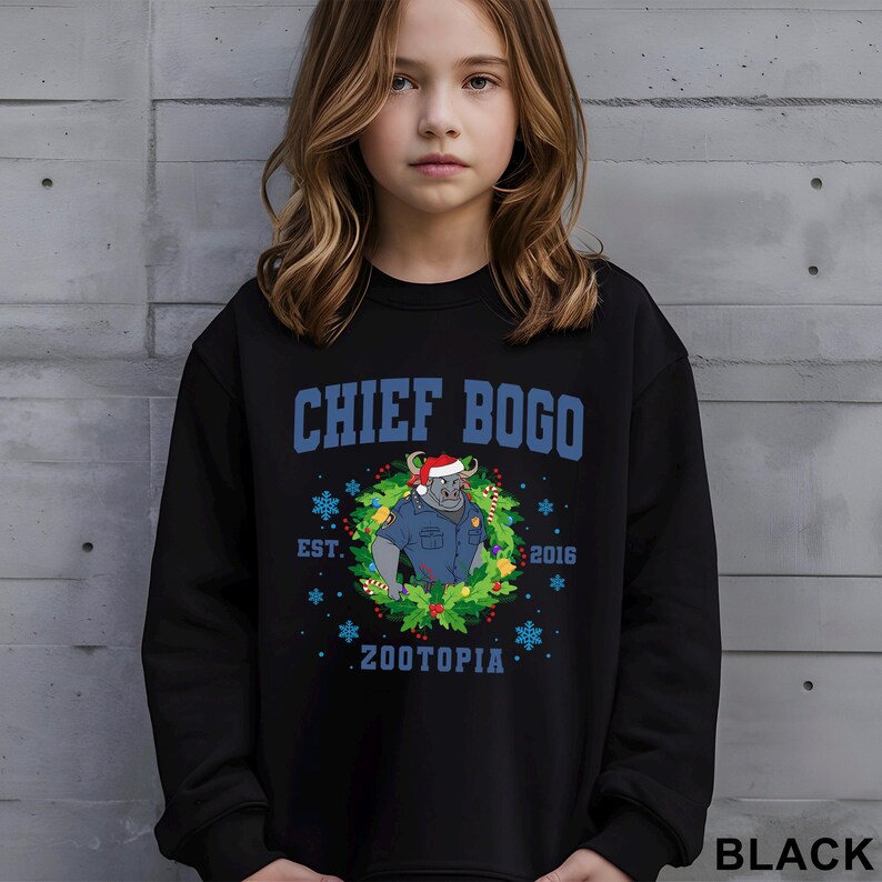 Op de afbeelding: Zwarte sweatshirt met de blauwe tekst "CHIEF BOGO" en een cartoon stier met een kerstmuts en politie-uniform in een krans. Bevat "EST. 2016" en "ZOOTOPIA". Het woord "BLACK" staat rechtsonder.