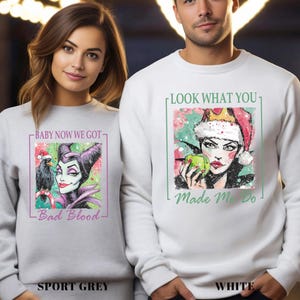 Puede incluir: Sudaderas deportivas grises y blancas con ilustraciones gr&aacute;ficas. La sudadera gris deportiva presenta una caricatura de una mujer con un cuervo y el texto "Baby Now We Got - Bad Blood". La sudadera blanca tiene una mujer con una corona y el texto "Look What You - Made Me Do".