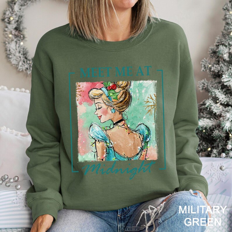 Puede incluir: Sudadera verde militar con una ilustraci&oacute;n en acuarela de una mujer con un vestido azul y el texto "Meet Me at Midnight". El dise&ntilde;o tiene un tema festivo navide&ntilde;o.