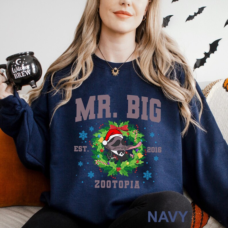 Op de afbeelding: Marineblauwe sweatshirt met de tekst "MR. BIG" in een bruin lettertype. Een stripfiguur met een kerstmuts staat in een krans met de tekst "ZOOTOPIA" eronder. De sweatshirt heeft ook de tekst "EST. 2016" en het woord "NAVY".