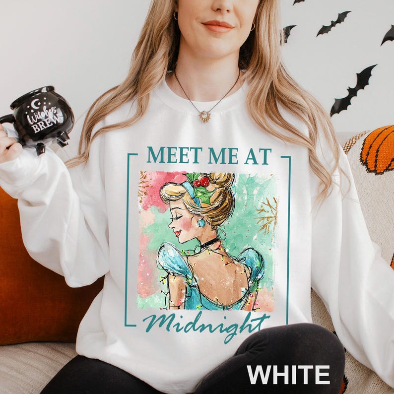 Puede incluir: Sudadera blanca con una ilustraci&oacute;n en acuarela de una mujer con un vestido azul y el texto "Meet Me At Midnight". El dise&ntilde;o incluye un borde y acentos turquesa. La palabra "WHITE" est&aacute; impresa en la parte inferior.