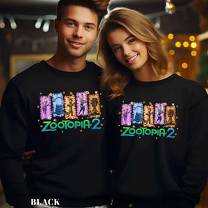 May include: Black sweatshirts featuring a colorful "Zootopia 2" graphic. The design includes various cartoon characters in rectangular frames. The text "BLACK" is at the bottom of the image.
