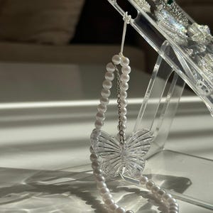 Pingente de borboleta de pérola feito à mão: acessório elegante para celular