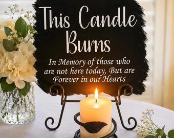 May include: A clear acrylic sign with a black painted center featuring white text that reads: This Candle Burns In Memory of those who are not here today, But are Forever in our Hearts. It sits on a black metal stand with a lit pillar candle.
