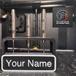 Może przedstawiać: Czarny stojak na lotki, wydrukowany w 3D, z białą tabliczką z napisem "Your Name". Stojak ma trzy miejsca na lotki i stoi na czarnej powierzchni.