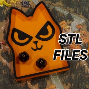 May include: An orange cat-shaped dice tray with black accents and two dice inside. The tray has the text "STL FILES" in white. The background shows a game board with miniature game pieces.